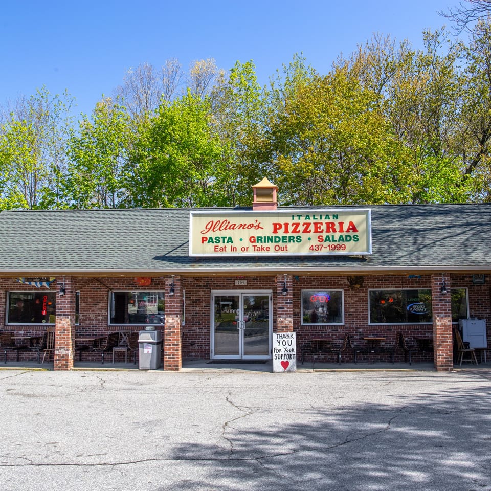 Illiano's Pizzeria, a brick building with a sign advertising Italian food, pasta, grinders, and salads.