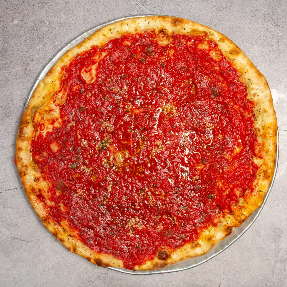 A large, round tomato pie with a thick red sauce and golden crust on a metal pan.