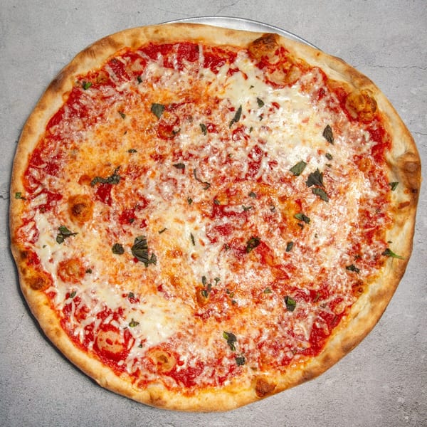 A whole cheese pizza with tomato sauce and fresh basil on a metal tray.