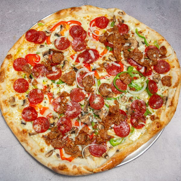A large, round pizza with pepperoni, sausage, mushrooms, onions, and bell peppers on a metal tray.